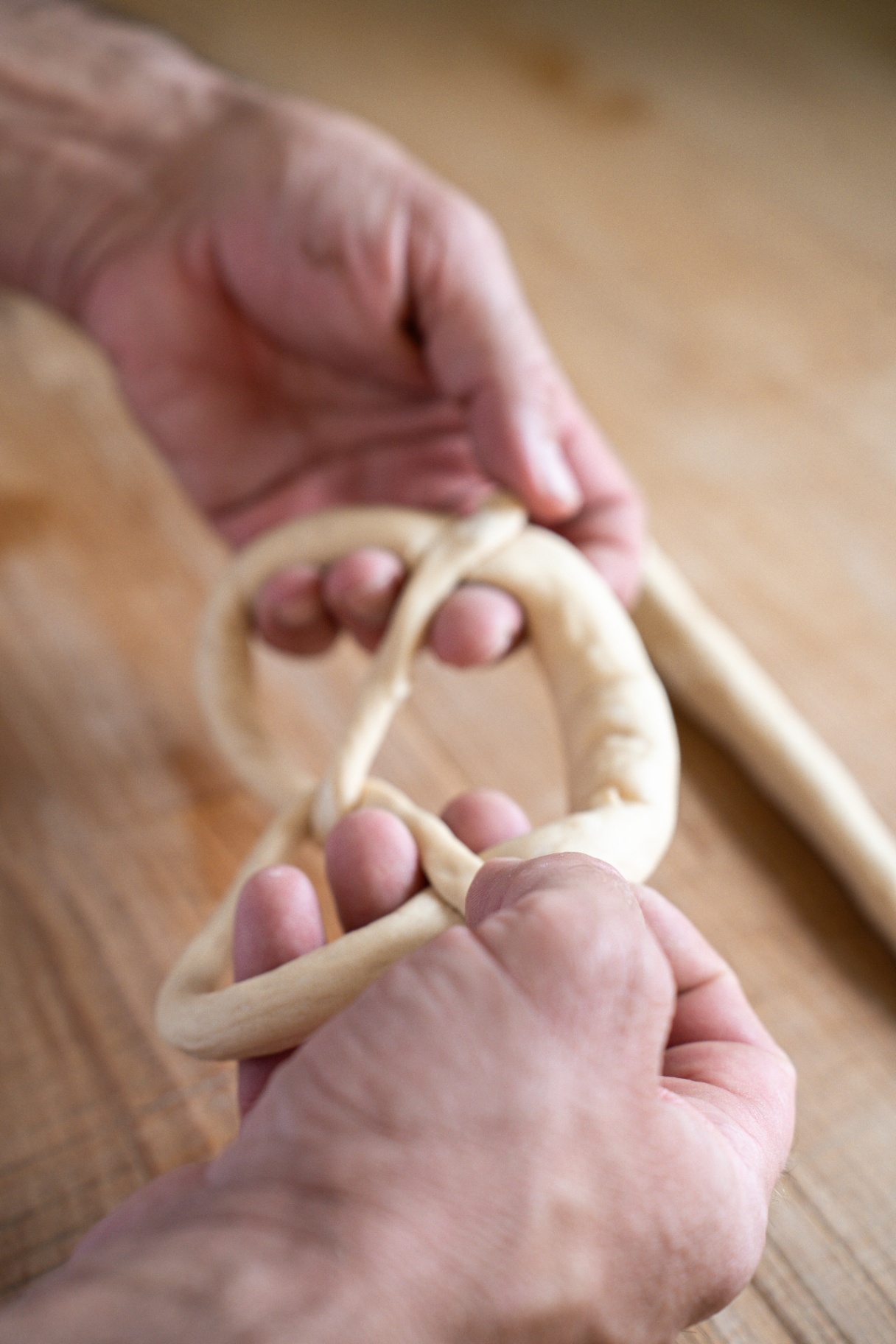 Bäcker schlingt eine Breze von Hand in der Backstube der Bäckerei Blab